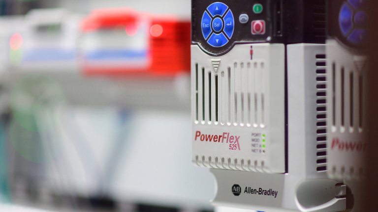 两台 PowerFlex 变频器的特写，这些变频器与背景中的其他组件一起在电气面板中通电。