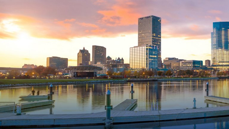View of the Milwaukee skyline at twilight with city reflection in lake Michigan and a harbor pier