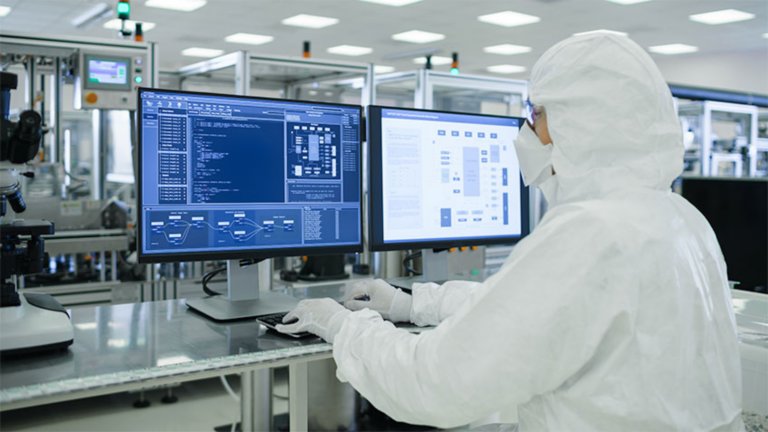 Gowned pharma worker at dashboard monitor
