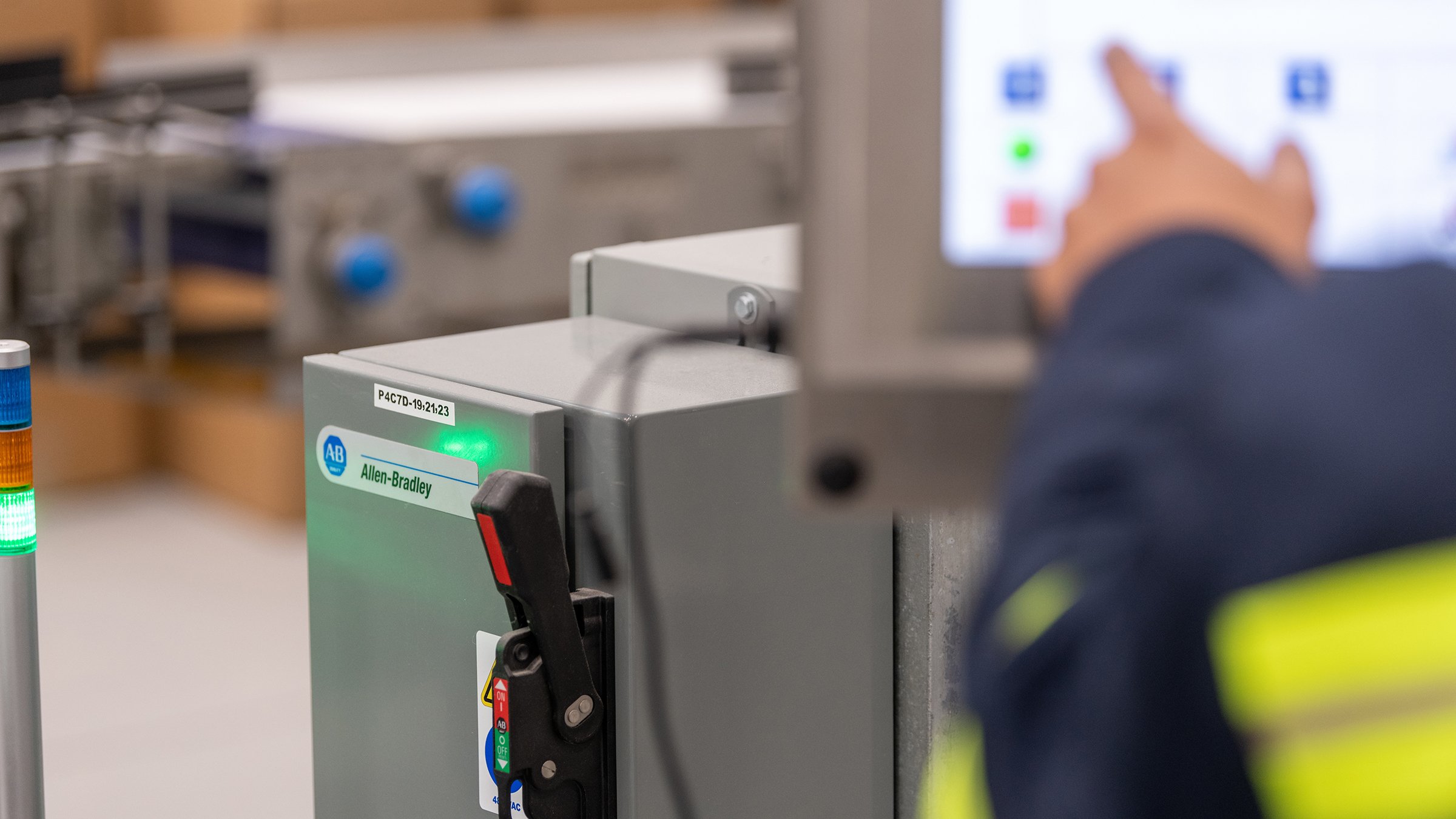 图中是一台 Allen-Bradley 控制器，技术人员的手正指向人机界面。Rockwell Automation 为 Allen-Bradley 产品提供产品和应用技术支持。2021 年 5 月 27 日星期四，俄亥俄州海勒姆市五大湖奶酪工厂